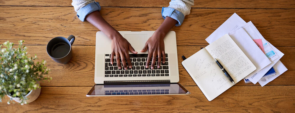 using a laptop next to open notebooks